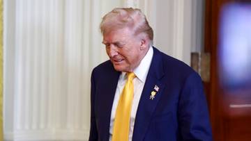 Donald Trump w garniturze i ż&oacute;łtym krawacie z teczką w ręku