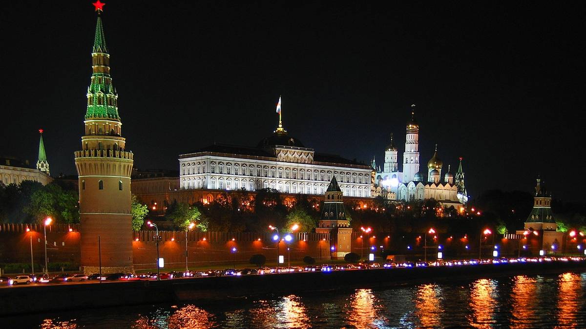 Widok na Kreml w Moskwie nocą, z oświetlonymi budynkami i wieżami.