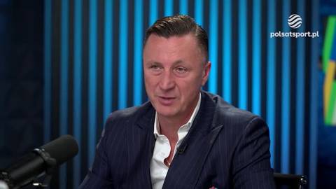 Tomasz Hajto w garniturze siedzi w studiu telewizyjnym, skierowany lekko w prawo i mówiący. Za nim znajduje się niebieskie tło z pionowymi pasami i logo Polsat Sport.