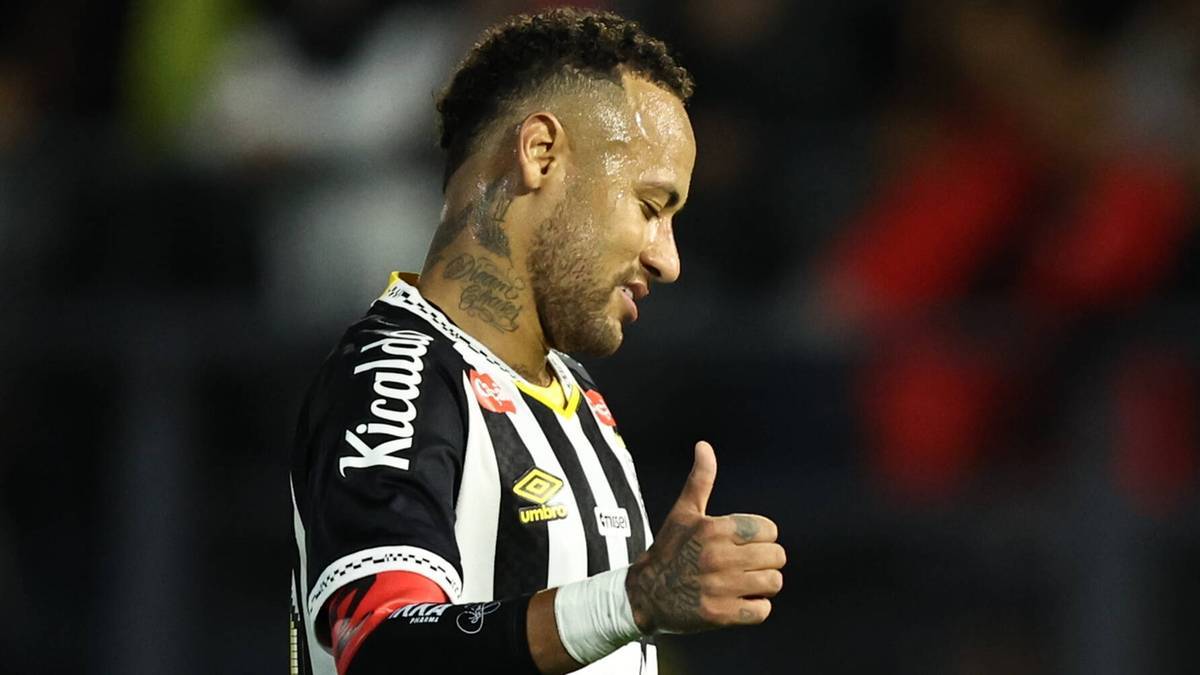 Neymar w koszulce piłkarskiej z kciukiem w górze, patrzący w bok.