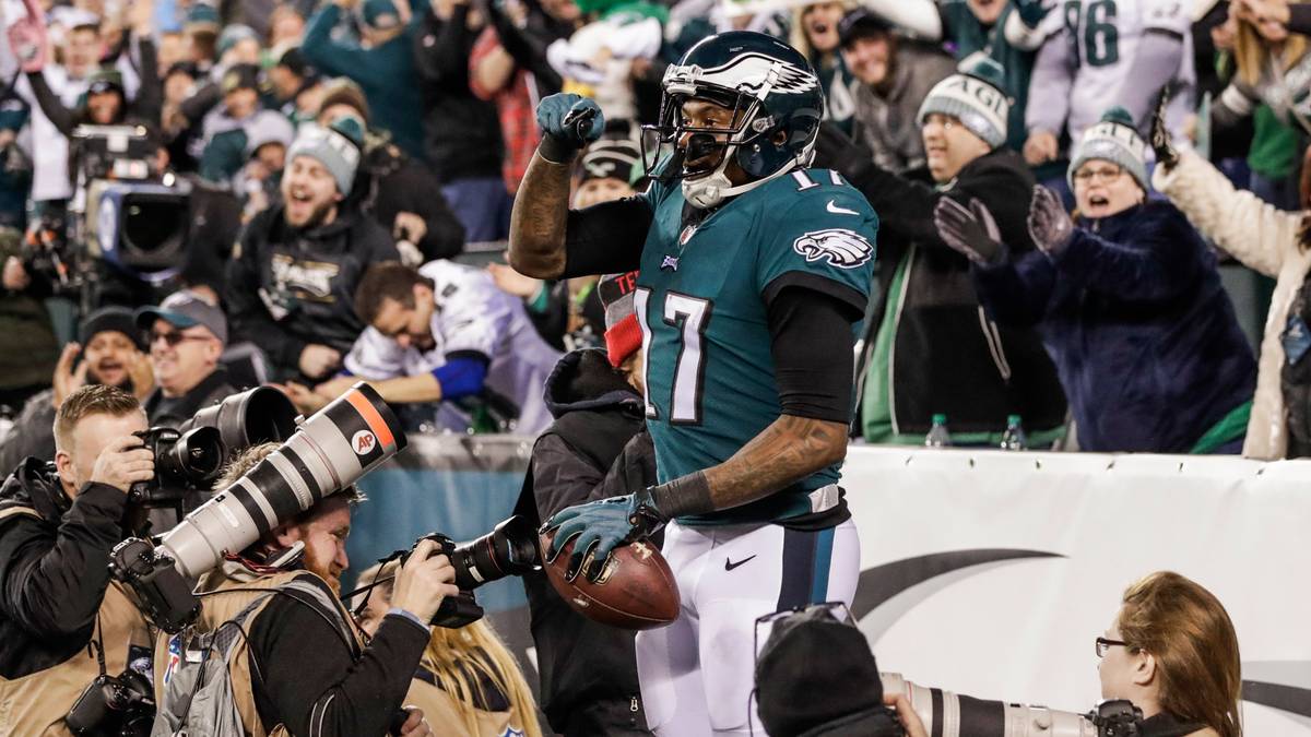 Gracz NFL w stroju Philadelphia Eagles świętuje zwycięstwo na boisku, otoczony przez kibic&oacute;w i fotograf&oacute;w.