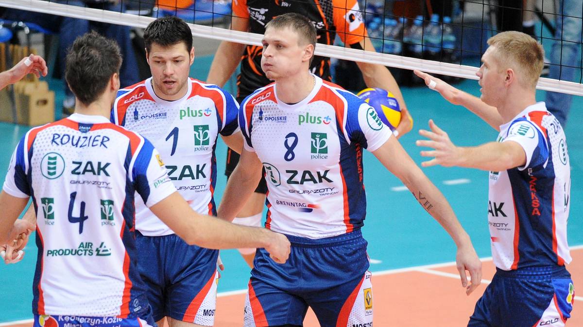 Siatkarze w białych i niebieskich strojach sportowych podczas meczu lub treningu siatkarskiego.