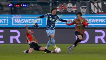 Trzech piłkarzy podczas meczu piłki nożnej. Jeden z nich leży na ziemi, drugi pr&oacute;buje odebrać piłkę trzeciemu, kt&oacute;ry ją kontroluje.