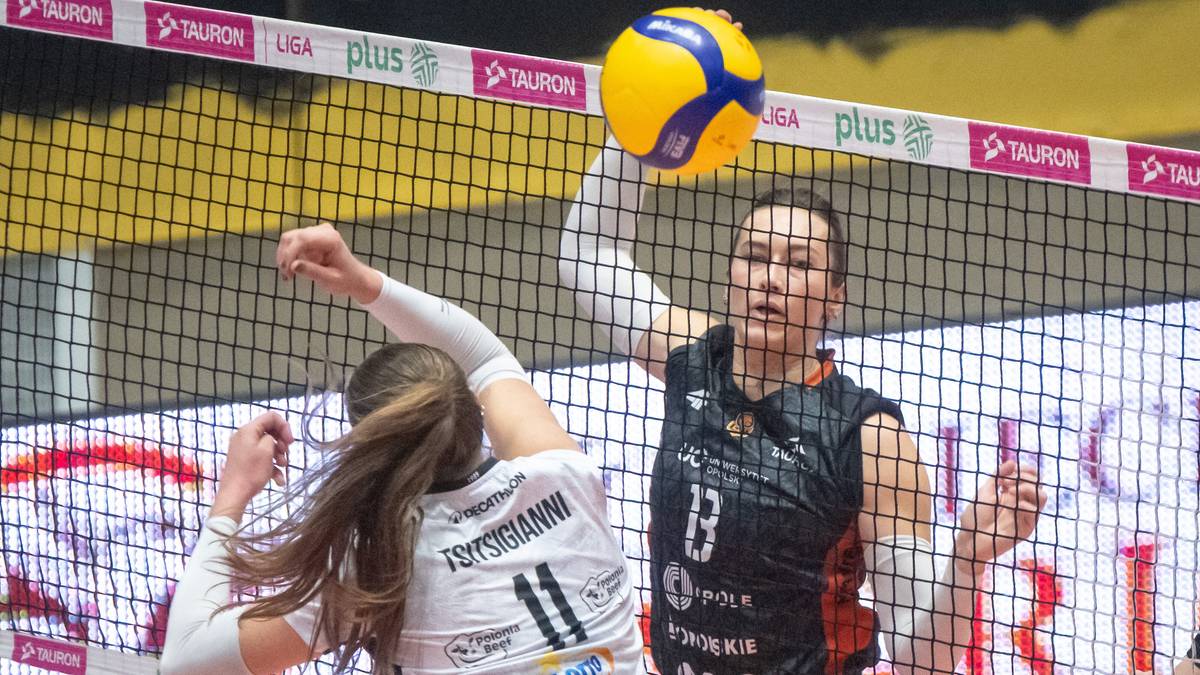 Dwie siatkarki rywalizują przy siatce, jedna próbuje zablokować atak drugiej.
