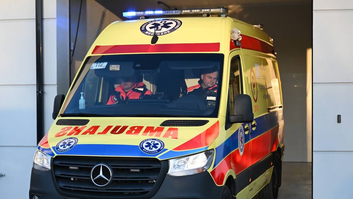 Karetka pogotowia ratunkowego z włączonymi sygnałami świetlnymi wyjeżdża z garażu.