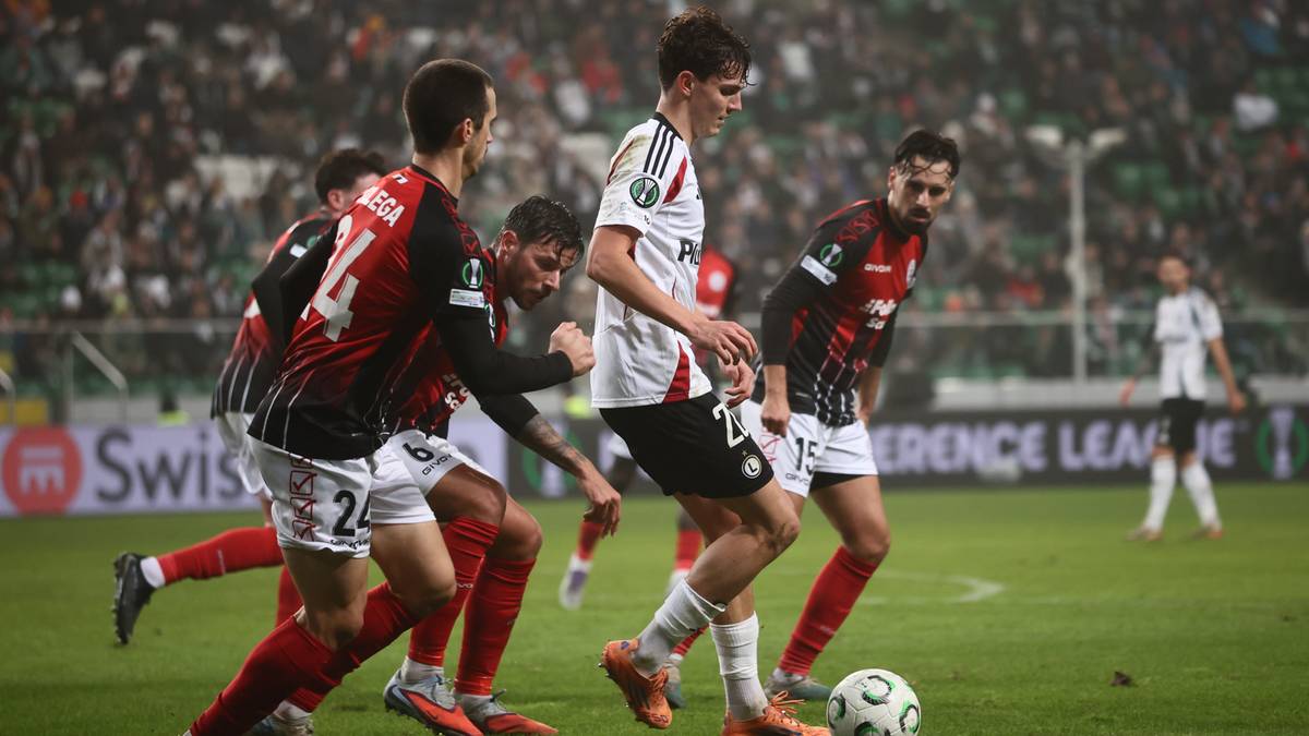 Piłkarze rywalizujący o piłkę na boisku podczas meczu.