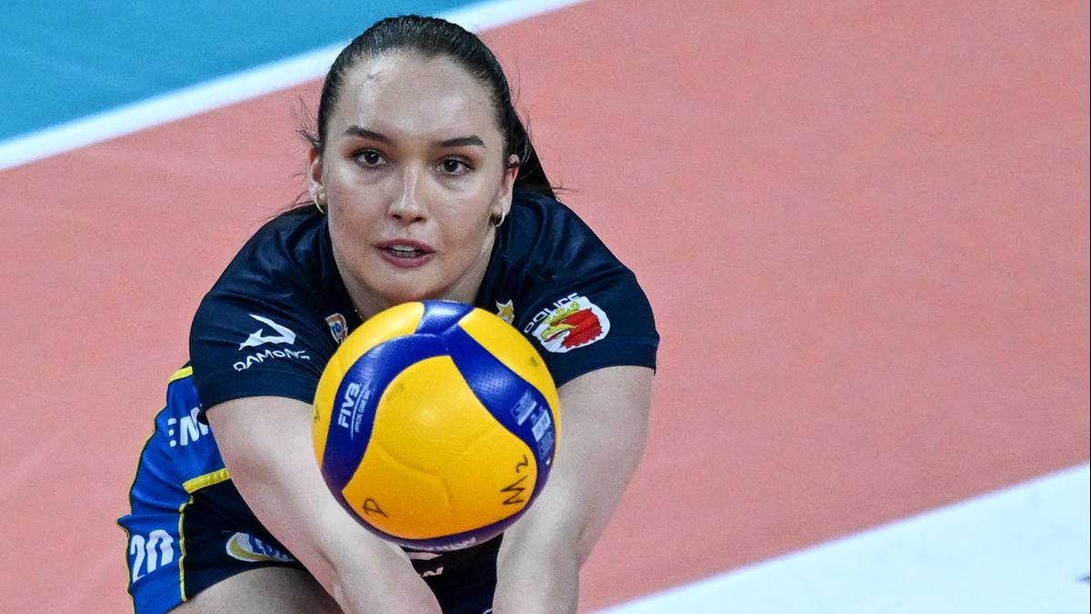 Kobieta w stroju sportowym trzyma piłkę do siatk&oacute;wki, gotowa do podania lub przyjęcia.