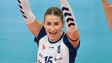 Siatkarki w białych koszulkach z niebieskimi elementami cieszą się ze zwycięstwa, podnosząc ręce do g&oacute;ry.