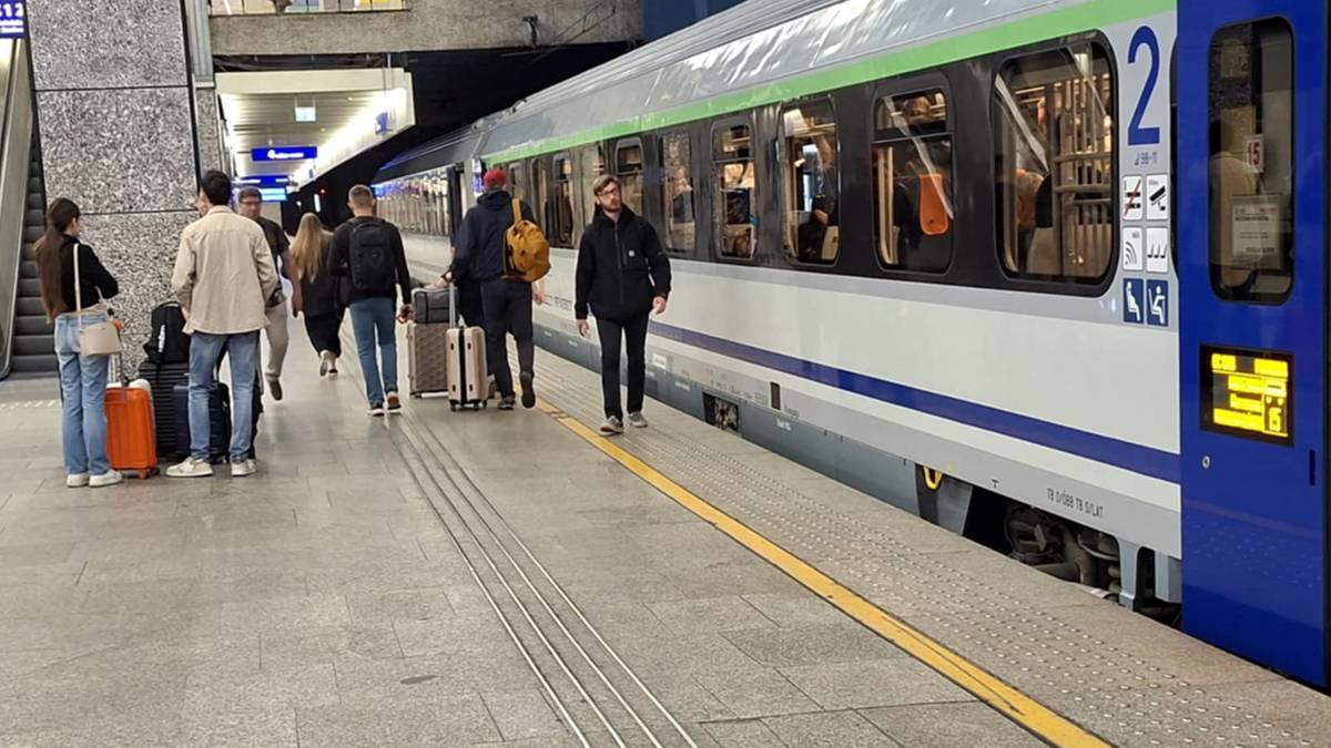 Pasażerowie z bagażami stoją na peronie dworca kolejowego obok pociągu.