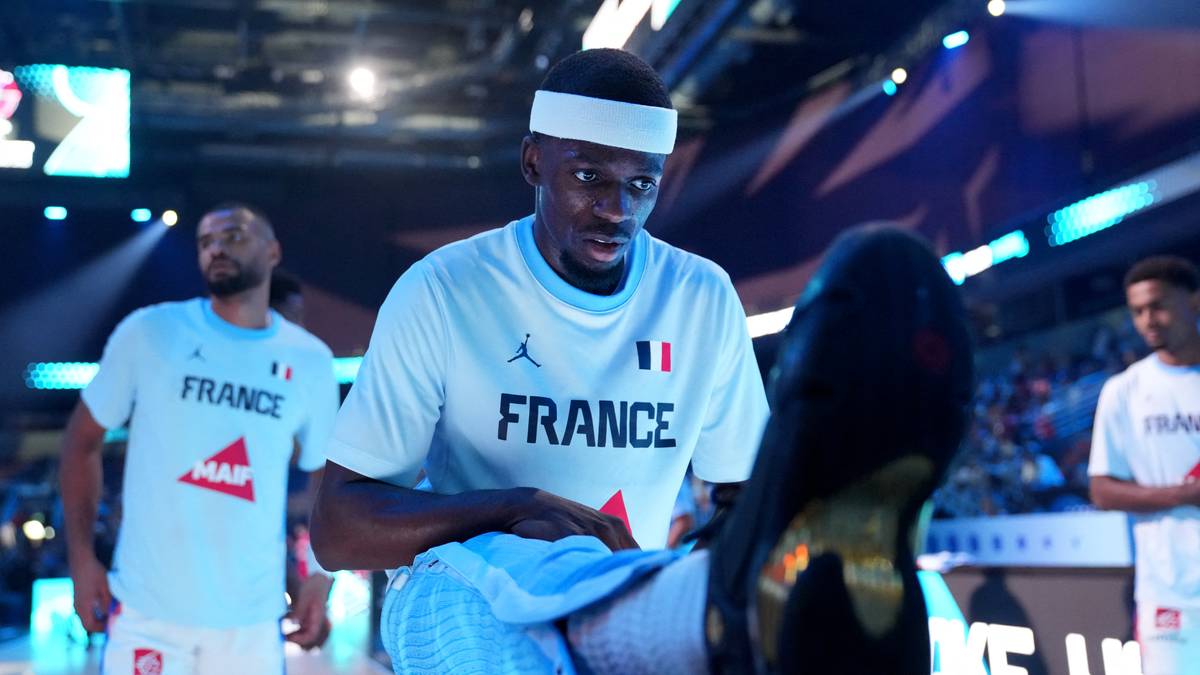 Trzech mężczyzn w koszulkach "FRANCE", dwóch z nich patrzy na siebie z wyrazem koncentracji.