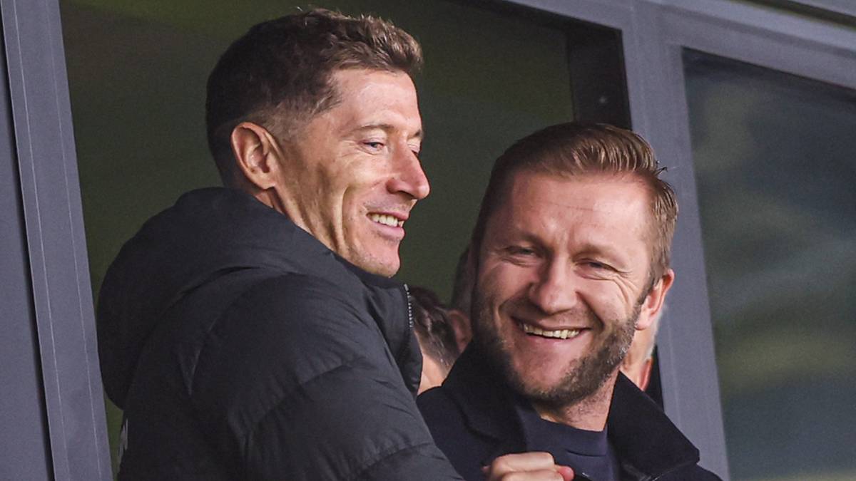 Dwóch mężczyzn ogląda mecz, jeden z nich to Robert Lewandowski.