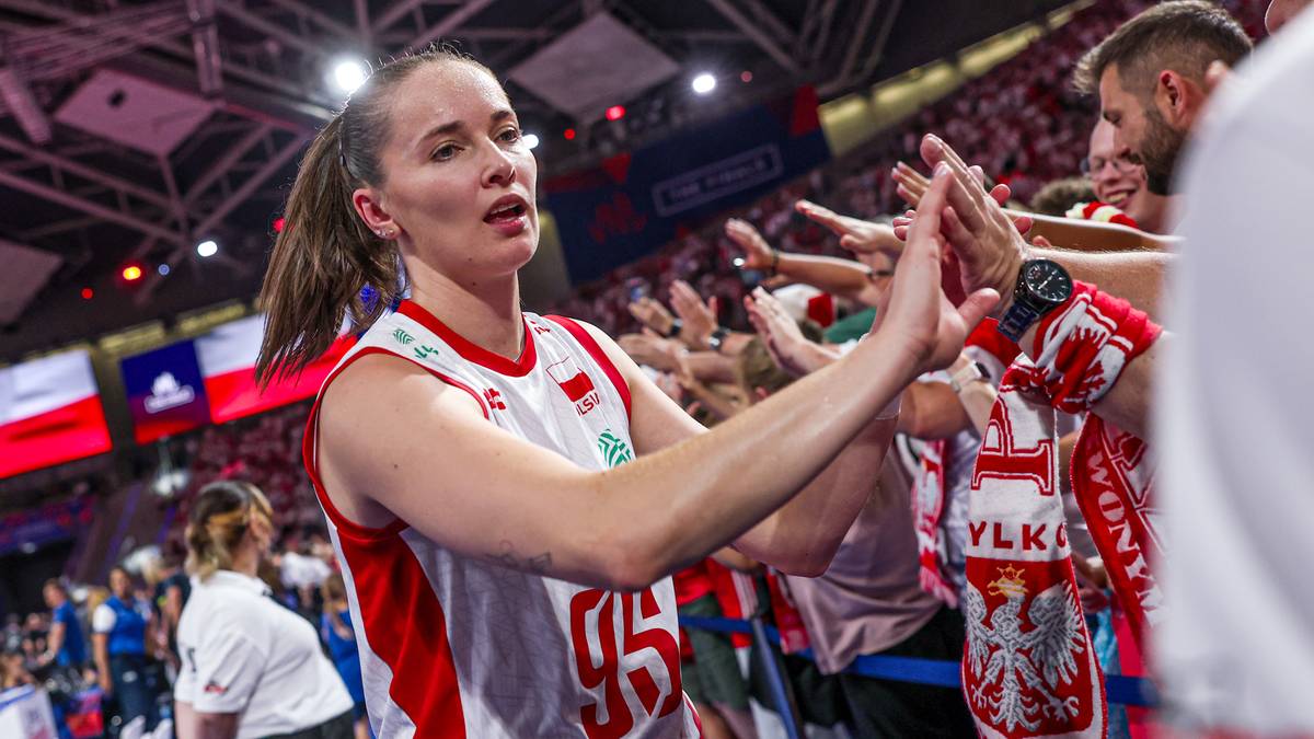 Siatkarka w biało-czerwonym stroju z numerem 95 na plecach daje "piątkę" kibicowi. W tle widać trybuny wypełnione kibicami.