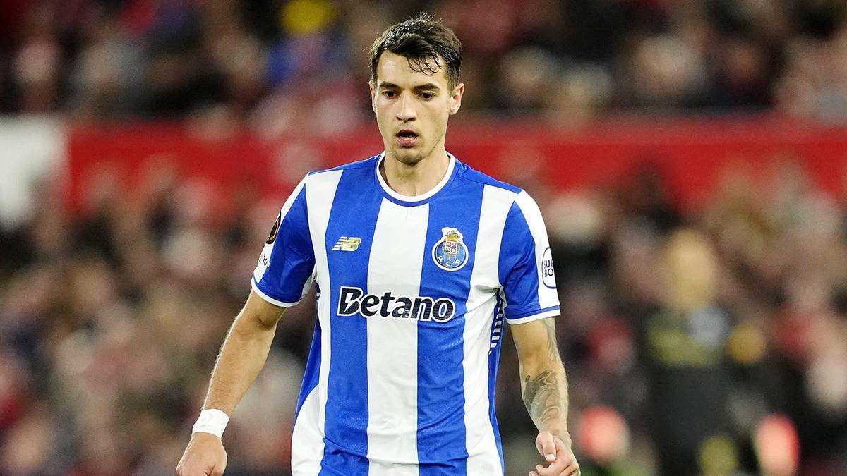 Piłkarz w niebiesko-białej koszulce FC Porto z logo "Betano" stoi na boisku.