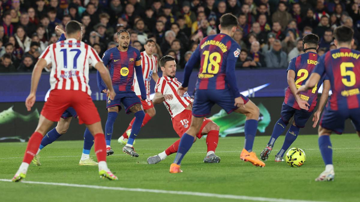 Piłkarze w strojach FC Barcelony i Atletico Madryt grają w piłkę nożną na boisku przed trybunami kibiców.