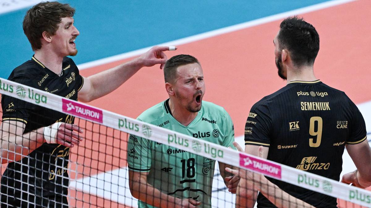 Siatkarze w trakcie meczu, jeden z nich rozmawia z kolegą z drużyny przy siatce.