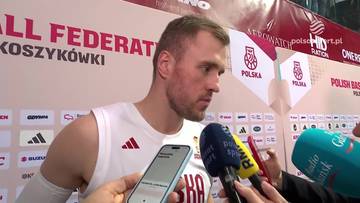 Mikołaj Witliński, koszykarz w białej koszulce z trzema paskami Adidasa, udziela wywiadu. Na jego koszulce widoczne jest logo "ADIDAS" i fragment napisu w języku polskim. W tle znajdują się logotypy "POLSKA" i "POLISH BASKETBALL FEDERATION". Koszykarz trzyma w dłoniach smartfon.