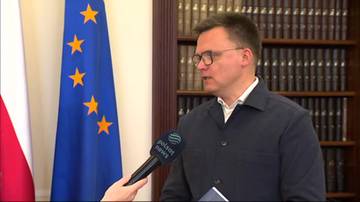 Szymon Hołownia udziela wywiadu z mikrofonem Polsat News w tle z flagą Unii Europejskiej.