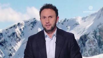 Konrad Niedźwiedzki, mężczyzna w garniturze, na tle ośnieżonych gór.