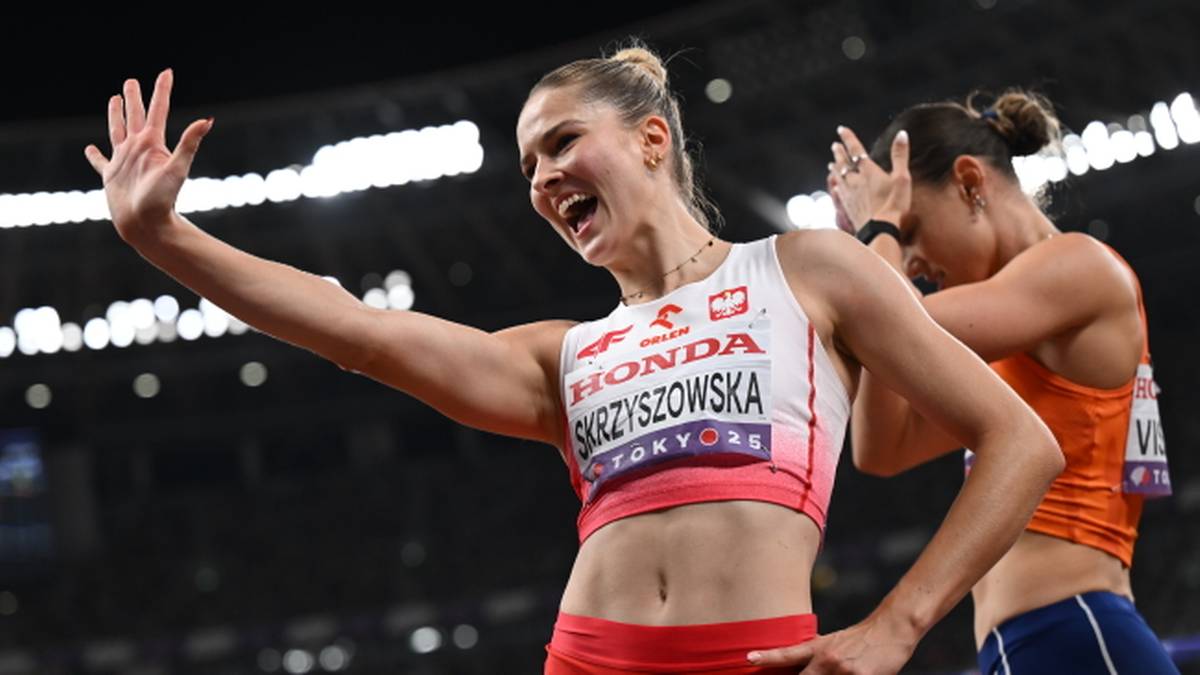 Lekkoatletka Pia Skrzyszowska uśmiecha się i macha ręką do publiczności, ubrana w biały sportowy top z napisem "HONDA SKRZYszOWSKA TOKYO 2020". Z tyłu widać inną zawodniczkę.