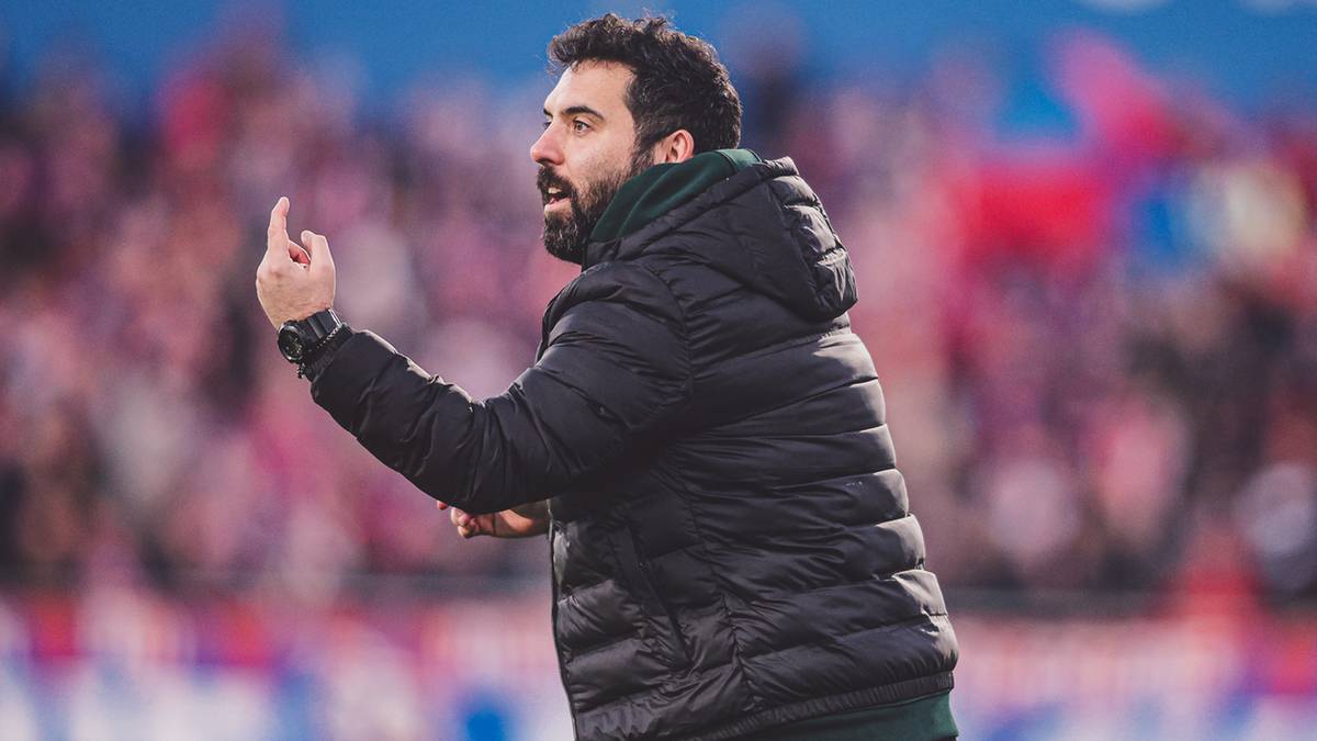 Trener piłkarski Goncalo Feio w kurtce zimowej z kapturem, gestykuluje ręką podczas meczu na boisku.