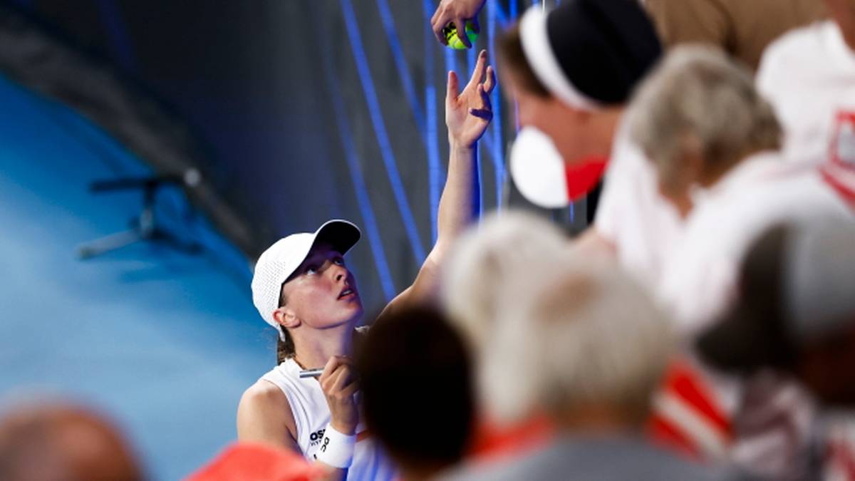 Iga Świątek podaje piłkę kibicom na trybunach.