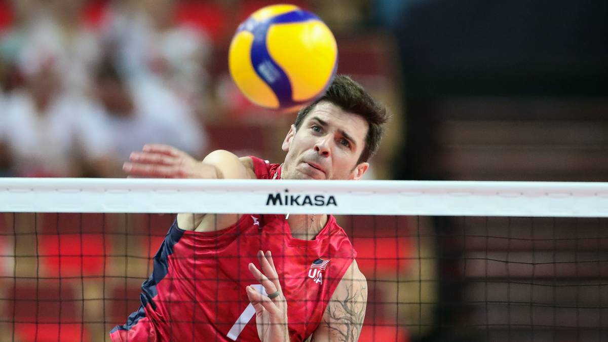 Siatkarz odbija piłkę nad siatką podczas meczu.