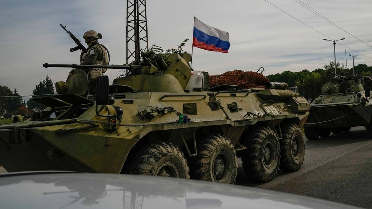 Rosyjski transporter opancerzony z żołnierzem na pokładzie, na kt&oacute;rym powiewa rosyjska flaga.