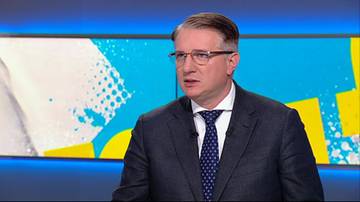 Przemysław Wipler w garniturze i krawacie, w okularach, patrzy w bok z poważnym wyrazem twarzy.