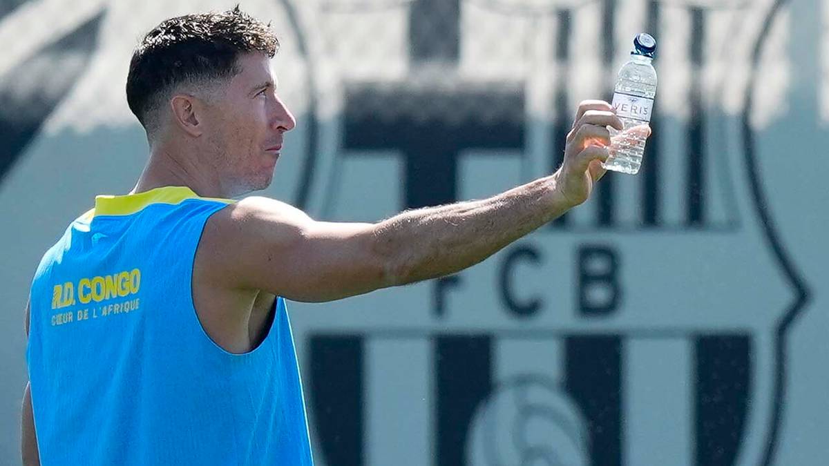 Piłkarz FC Barcelony z butelką wody w dłoni, na tle herbu klubu.