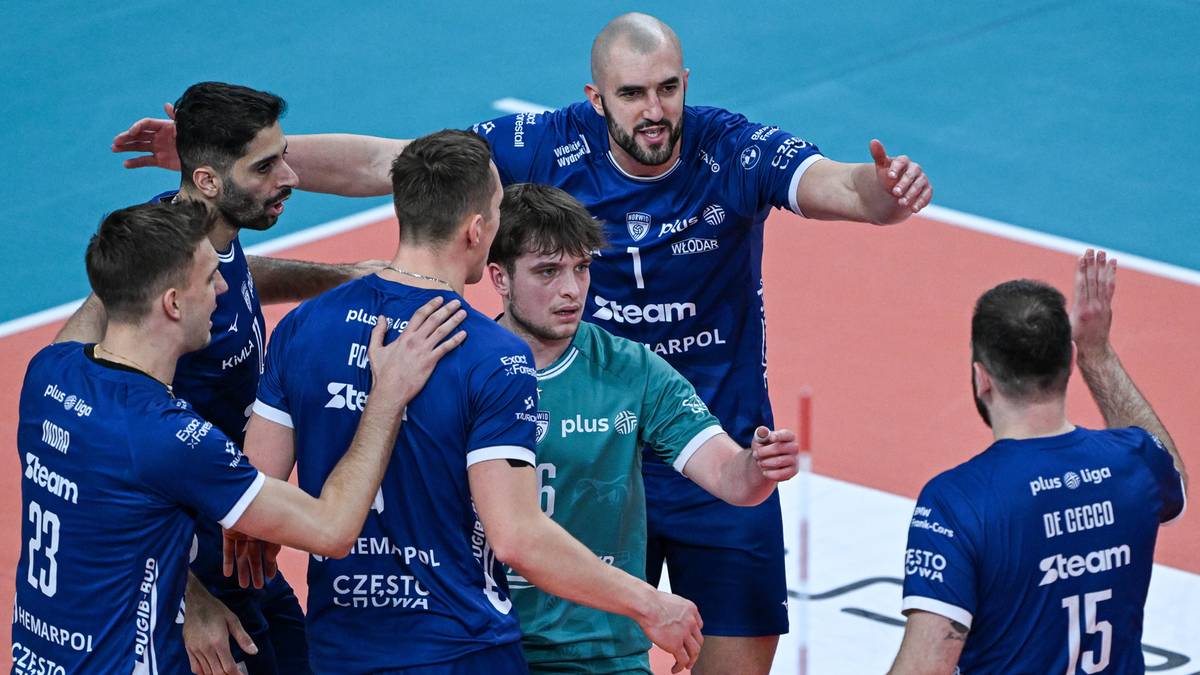 Grupa siatkarzy w niebieskich strojach drużynowych świętuje razem na boisku.