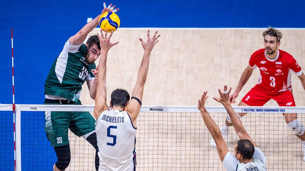 Siatkarze w akcji podczas meczu, jeden z nich wyskakuje do ataku z piłką w rękach, inni próbują go zablokować przy siatce.