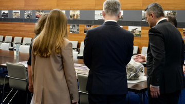 Fragmenty drona na stole, oglądane przez ludzi.