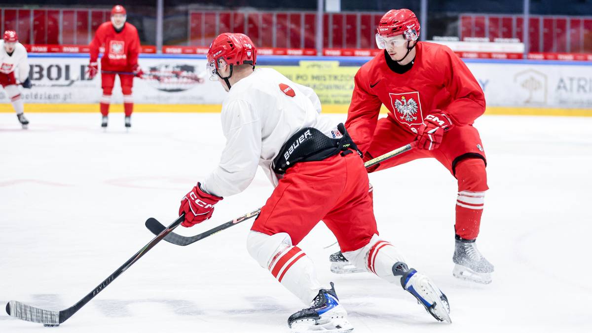 Dw&oacute;ch hokeist&oacute;w w czerwono-białych strojach z orzełkiem na piersiach na lodowisku.