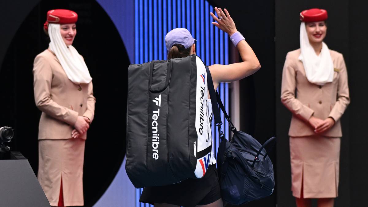 Tenisistka Iga Świątek z torbą sportową przechodzi obok dw&oacute;ch stewardes w uniformach Emirates.