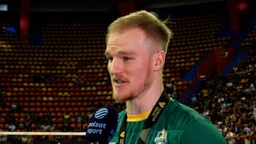 Mężczyzna z blond włosami, ubrany w zieloną koszulkę sportową, udziela wywiadu z mikrofonem przed trybunami pełnymi widz&oacute;w.