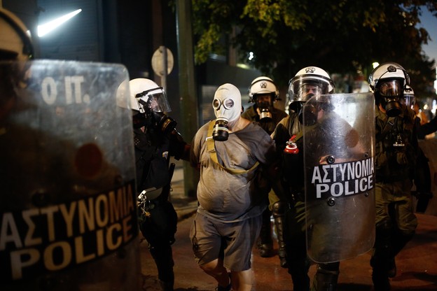 Policjanci zatrzymują demonstranta podczas starć po antyszczepionkowym wiecu w Atenach