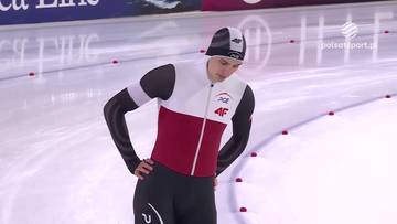 Sportowiec w stroju do łyżwiarstwa szybkiego stoi na lodowisku z rękami na biodrach.