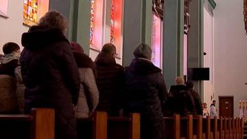 Grupa os&oacute;b siedzących w kościele, patrzących w stronę ołtarza.