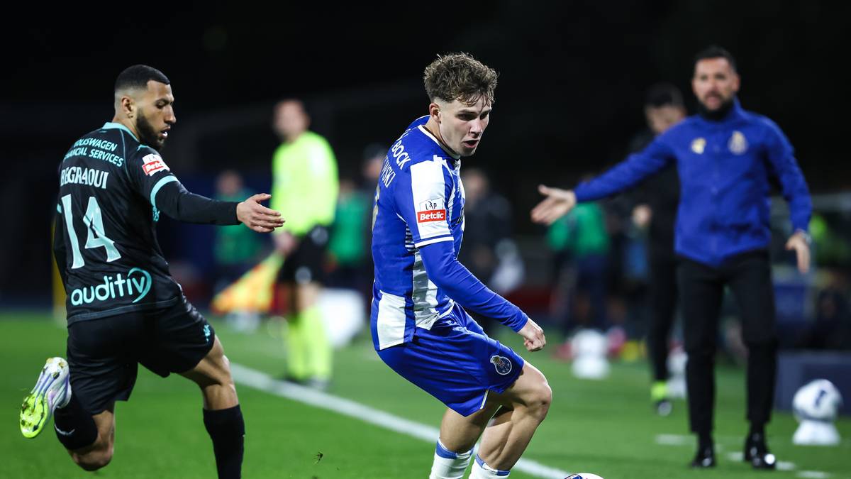 Piłkarz w niebiesko-białym stroju FC Porto drybluje z piłką, podczas gdy obrońca w czarnym stroju stara się mu przeszkodzić.