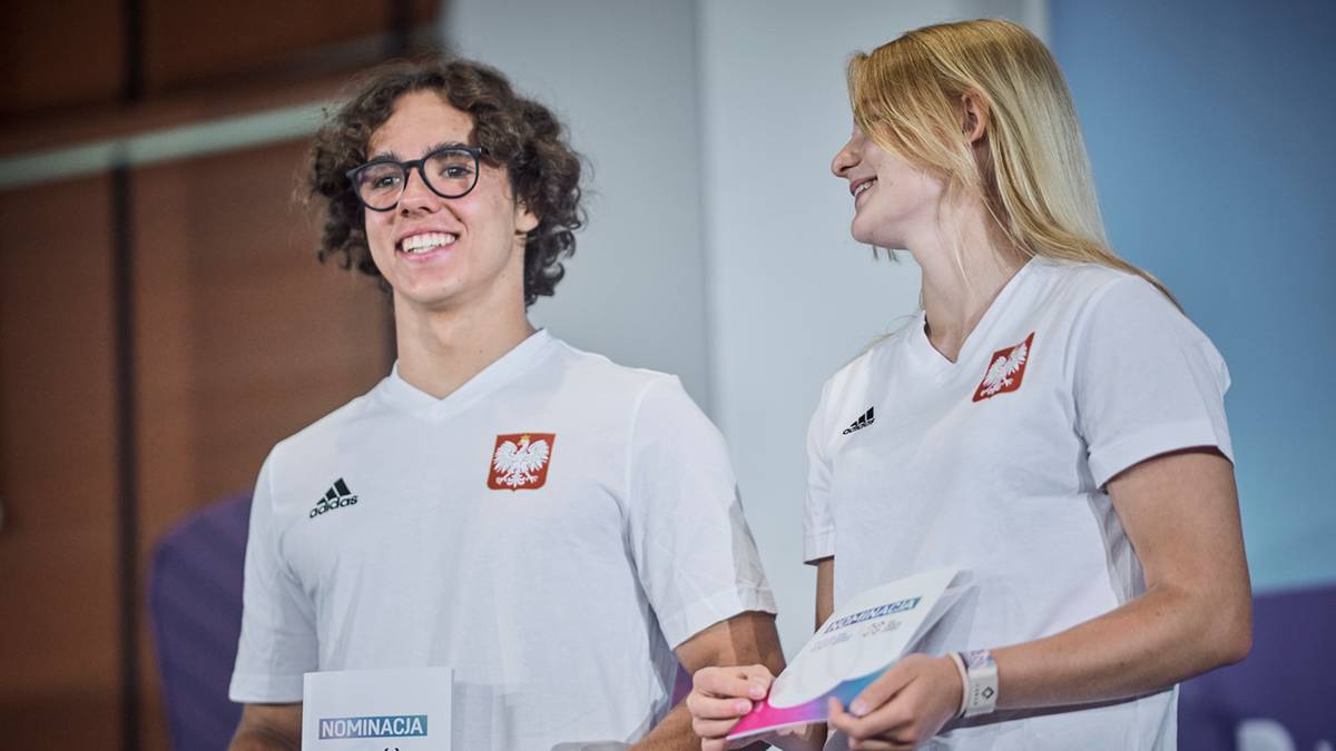 Młody mężczyzna i kobieta w białych koszulkach z godłem Polski, uśmiechają się.