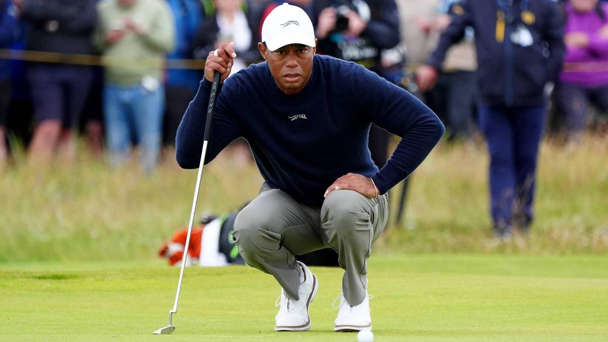 Tiger Woods klęczy na polu golfowym z kijem w ręku, skupiony na zagraniu.