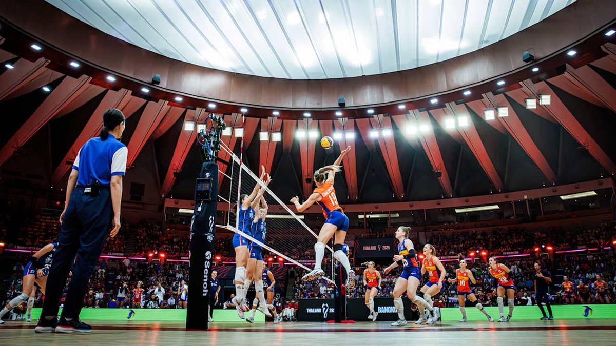 Siatkarki rozgrywają mecz w dużej, oświetlonej hali sportowej przed liczną publicznością.