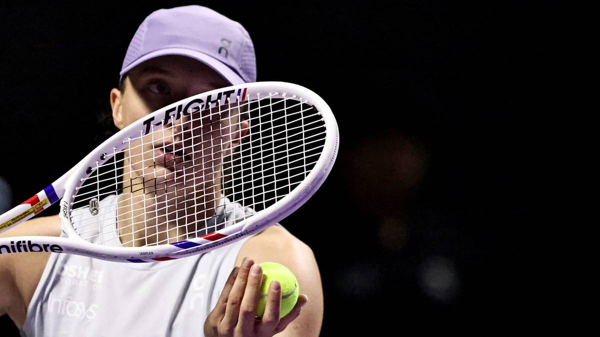Tenisistka Iga Świątek trzyma rakietę i piłkę tenisową podczas meczu.