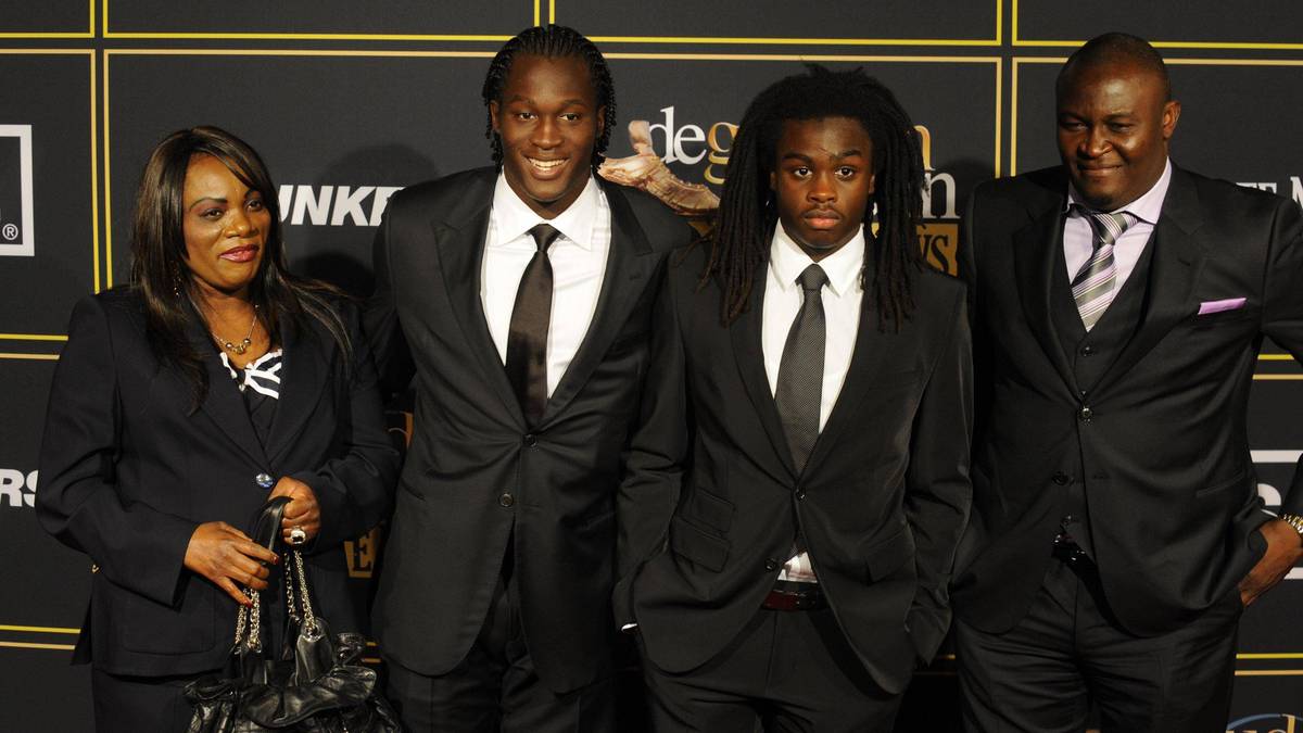 Cztery osoby w garniturach, w tym dwie kobiety i dwóch mężczyzn, stoją na tle czarnej ściany z logotypami.