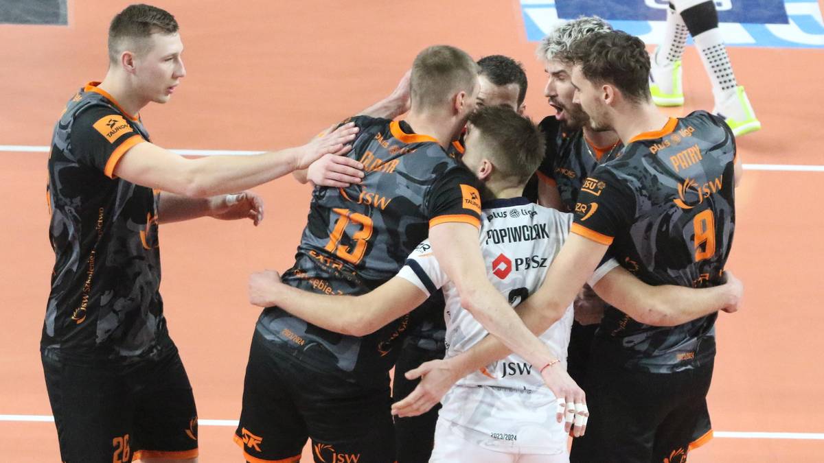 Siatkarze Jastrzębskiego Węgla świętują po zdobyciu punktu, otoczeni w uścisku na boisku.