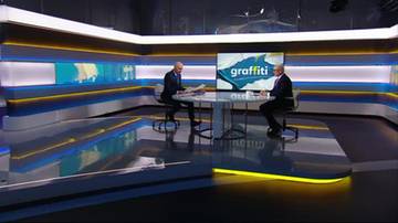 Dw&oacute;ch mężczyzn siedzi przy stole w studiu telewizyjnym, na ekranie widnieje napis "graffiti".