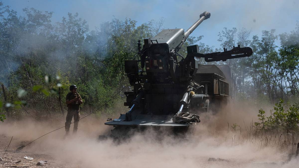 Działon armaty polowej w akcji, otoczony chmurą pyłu i dymu, z widocznym żołnierzem w pobliżu.