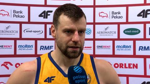 Portret mężczyzny w stroju sportowym, trzymającego mikrofon.