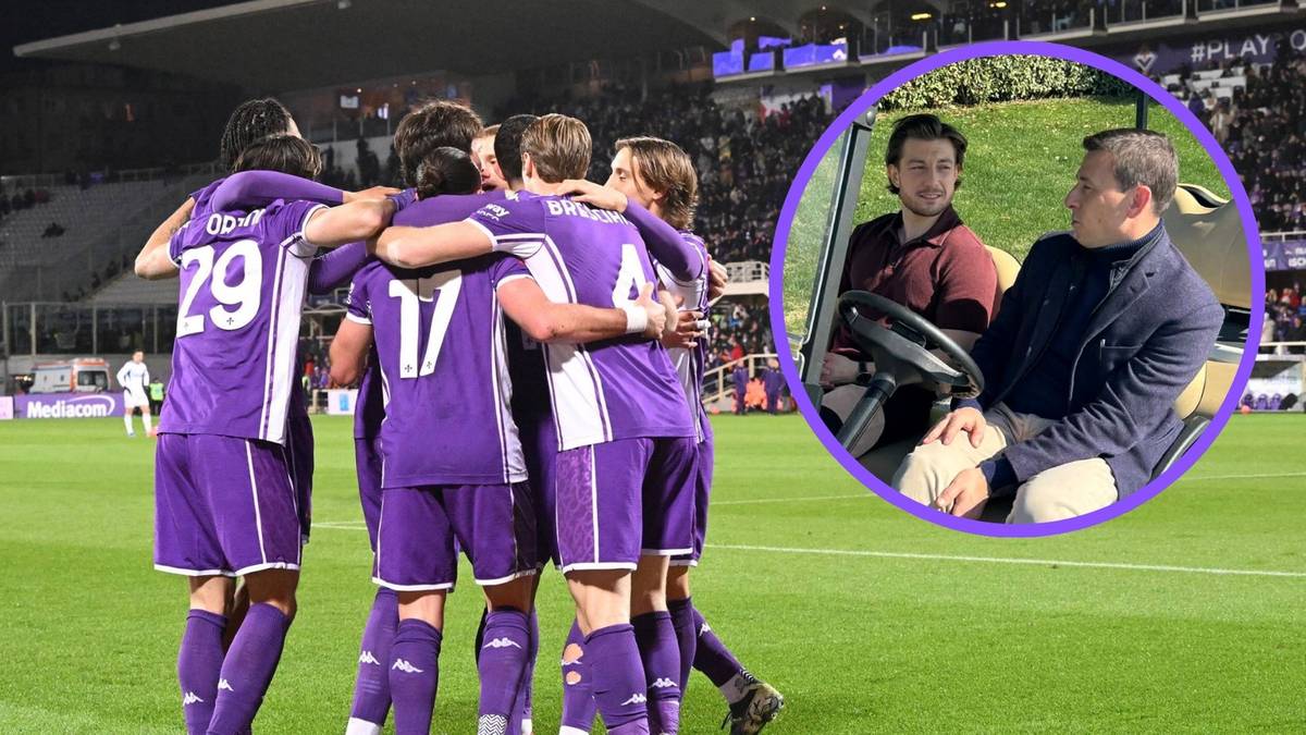 Dw&oacute;ch mężczyzn w okrągłej wstawce, jeden siedzi za kierownicą pojazdu golfowego, drugi obok, na tle stadionu piłkarskiego z zawodnikami w fioletowych strojach.