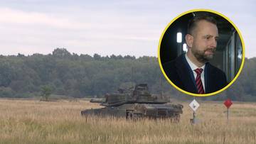 Czołg na polu z mężczyzną w garniturze w prawym górnym rogu.